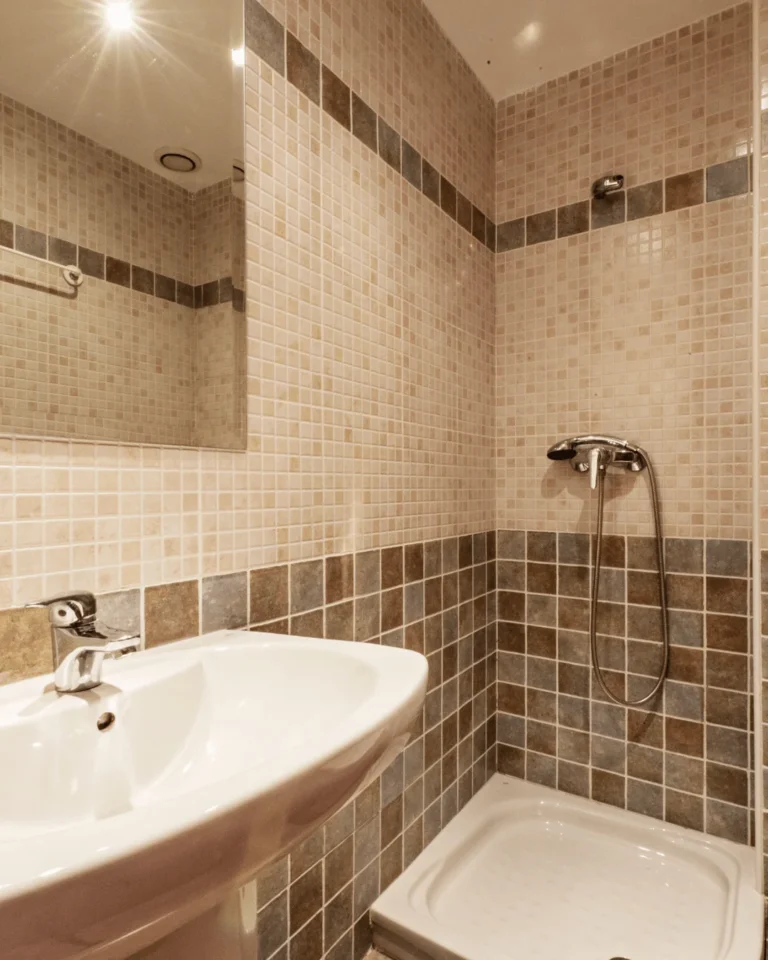 Salle de bain en faïence avec frise de mosaïque dans la douche